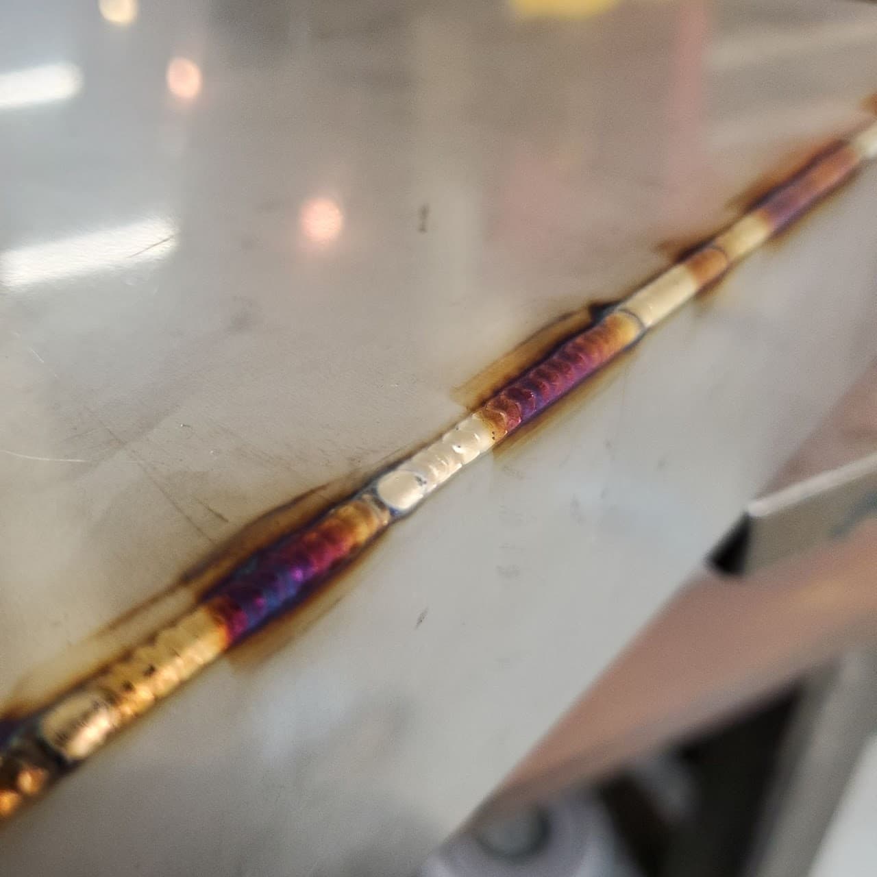 Close-up of a precision TIG weld bead with heat colors on stainless steel